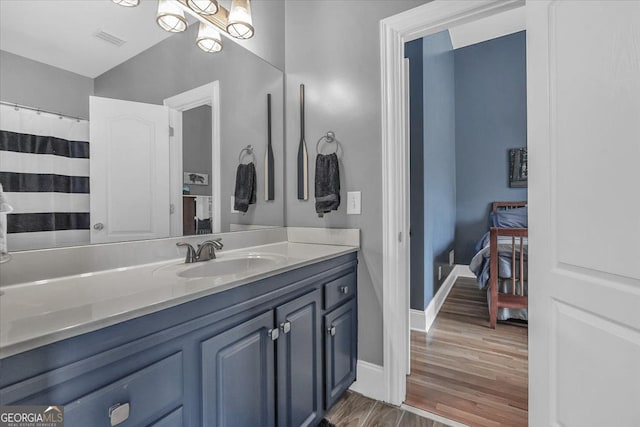 bathroom with baseboards, visible vents, vanity, and wood finished floors