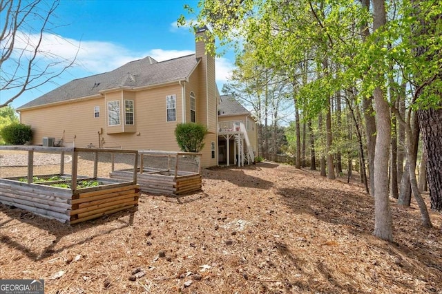 view of side of property with a vegetable garden, central AC, and a chimney