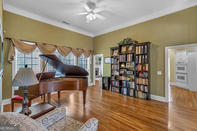 living area with ceiling fan, visible vents, crown molding, and wood finished floors