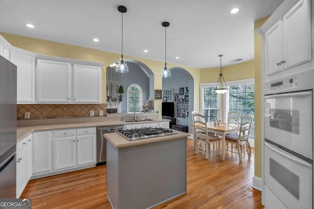 kitchen featuring light countertops, a sink, arched walkways, and appliances with stainless steel finishes