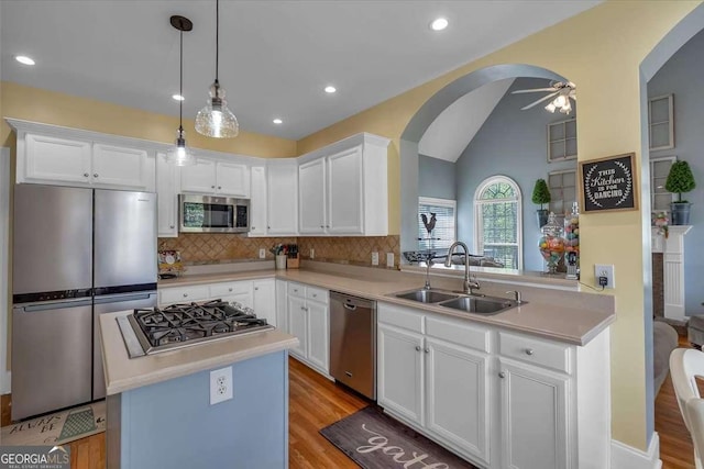kitchen featuring light countertops, stainless steel appliances, a ceiling fan, arched walkways, and a sink