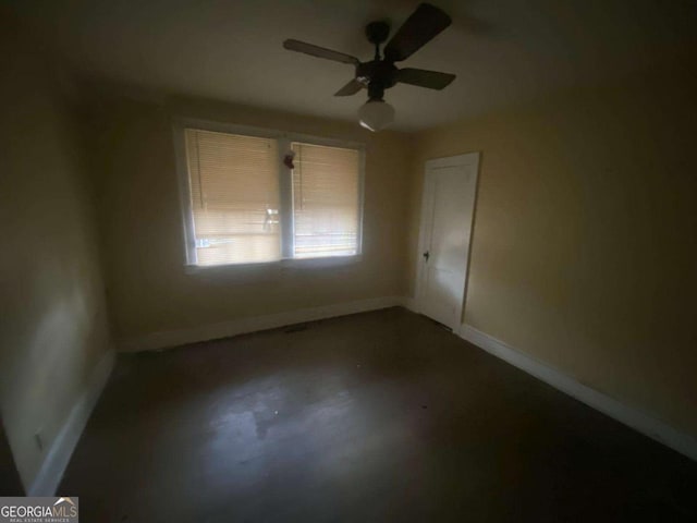 unfurnished room with a ceiling fan, concrete floors, and baseboards