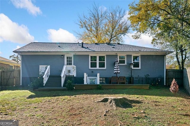back of property with a fenced backyard, brick siding, and a yard