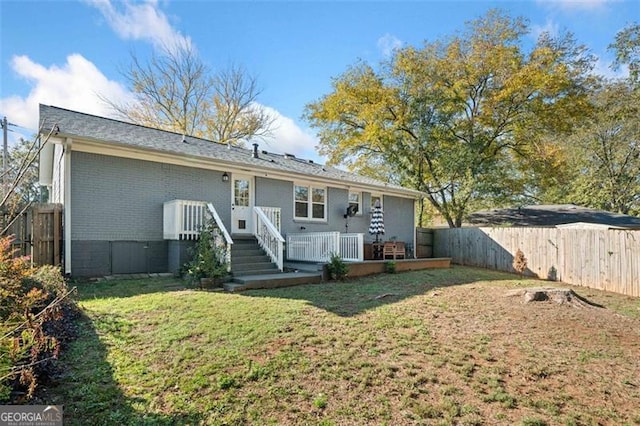 back of house with a lawn, brick siding, fence, and a wooden deck