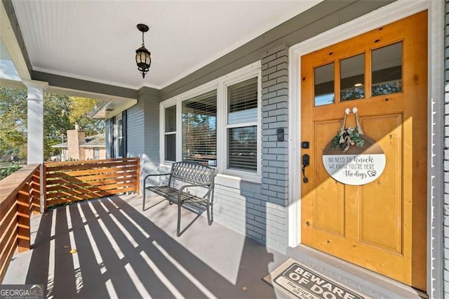 property entrance with a porch and brick siding