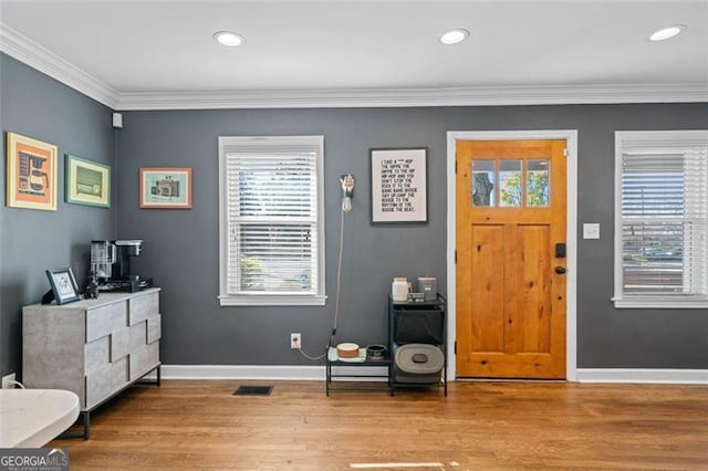 foyer with crown molding, wood finished floors, baseboards, visible vents, and recessed lighting