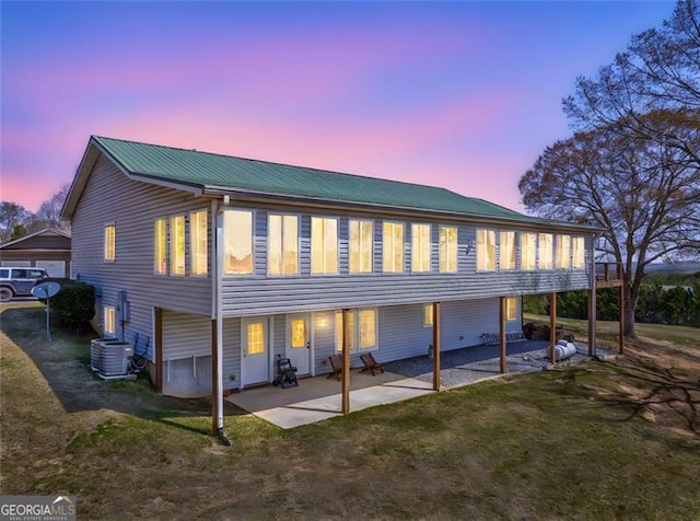 300 Ellis Rd, Rome, GA 30161 - back of house at dusk featuring a lawn, metal roof, cooling unit, and a patio area