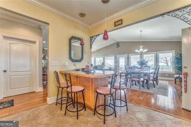 300 Ellis Rd, Rome, GA 30161 - kitchen featuring a breakfast bar area, light tile patterned floors, ornamental molding, baseboards, and hanging light fixtures