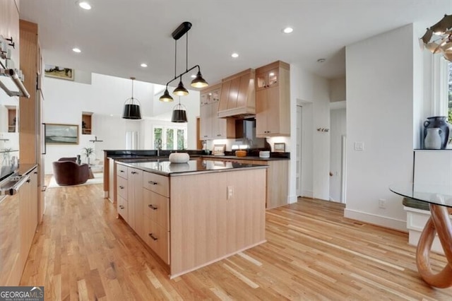 kitchen with light wood-type flooring, light brown cabinetry, glass insert cabinets, and dark countertops