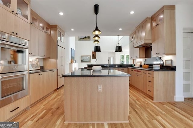 kitchen featuring light wood-style floors, dark countertops, light brown cabinetry, and stainless steel double oven