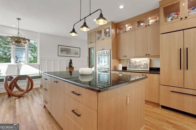 kitchen with light wood-style floors, light brown cabinets, fridge, and a center island