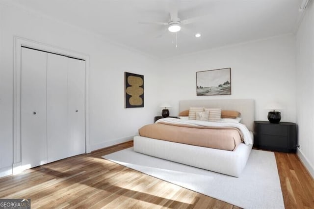 bedroom featuring baseboards, a closet, crown molding, a ceiling fan, and wood finished floors