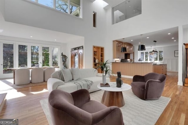 living area featuring light wood-style floors, a towering ceiling, and plenty of natural light