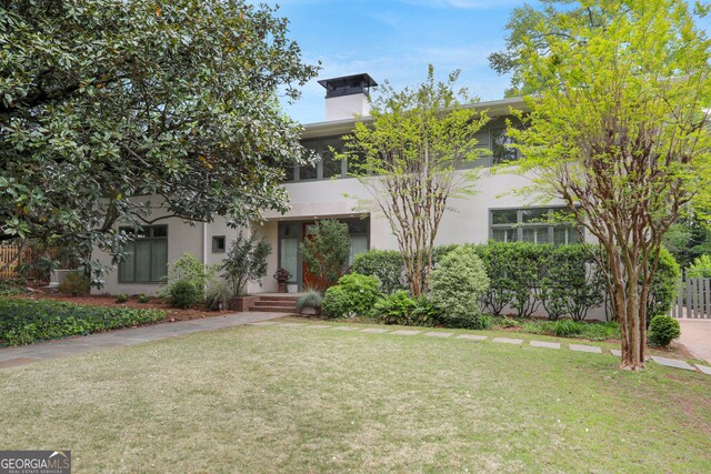 view of front of property with a front yard, stucco siding, and a chimney