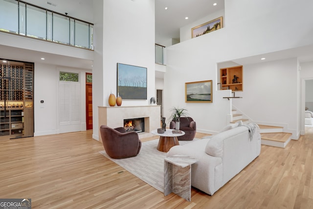 living area with a fireplace, light wood finished floors, a high ceiling, and baseboards