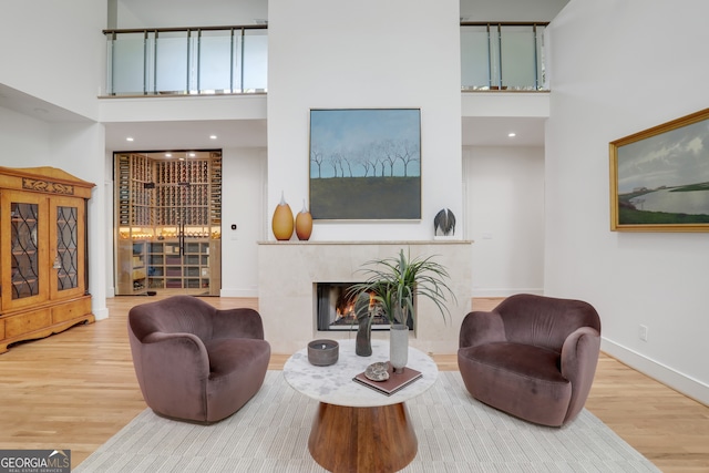 living area featuring baseboards, a tile fireplace, a high ceiling, and wood finished floors