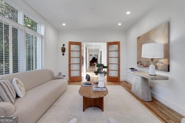 living area with recessed lighting, french doors, baseboards, and wood finished floors