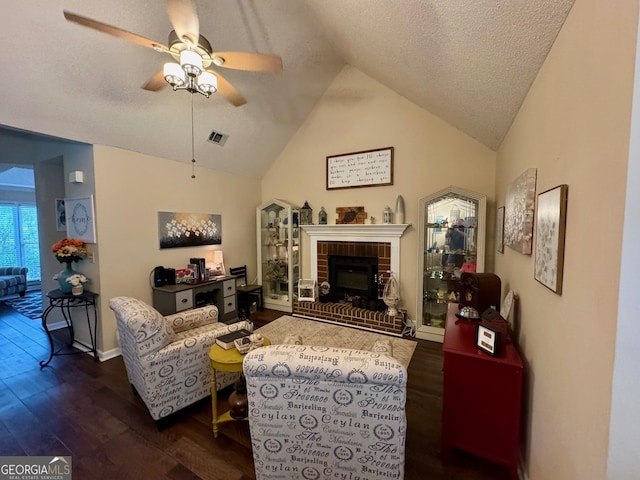living area featuring ceiling fan, dark wood-style flooring, a brick fireplace, vaulted ceiling, and a textured ceiling