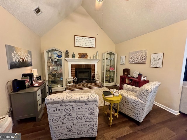 living area with vaulted ceiling, dark wood-style floors, baseboards, a fireplace, and a textured ceiling