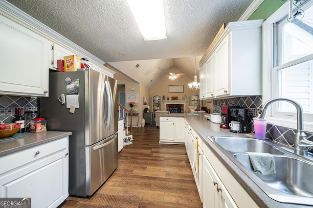 kitchen with a sink, freestanding refrigerator, white cabinets, ceiling fan, and a textured ceiling