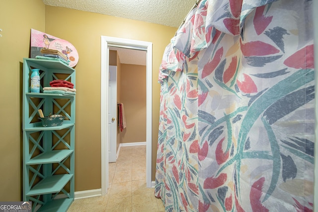 bathroom with a textured ceiling, tile patterned flooring, and baseboards