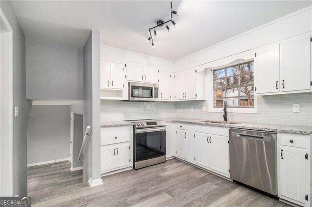 3862 Northstrand Dr, Decatur, GA 30035 - kitchen featuring tasteful backsplash, light wood-type flooring, a sink, white cabinets, and appliances with stainless steel finishes
