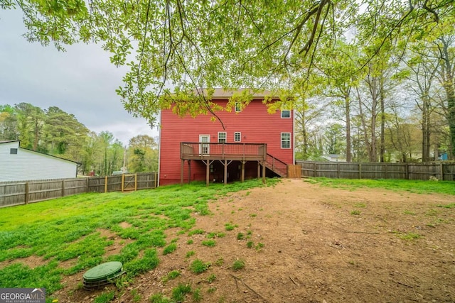 back of property with a lawn, a fenced backyard, stairway, and a deck