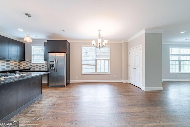 kitchen with ornamental molding, a chandelier, backsplash, appliances with stainless steel finishes, and wood finished floors