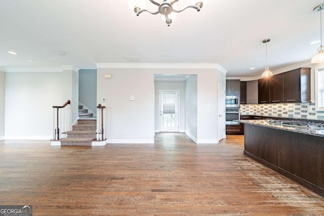 kitchen with ornamental molding, backsplash, dark brown cabinetry, appliances with stainless steel finishes, and wood finished floors
