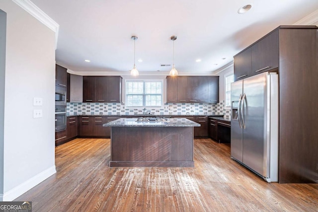 kitchen featuring light wood-style flooring, stainless steel appliances, dark brown cabinets, and tasteful backsplash
