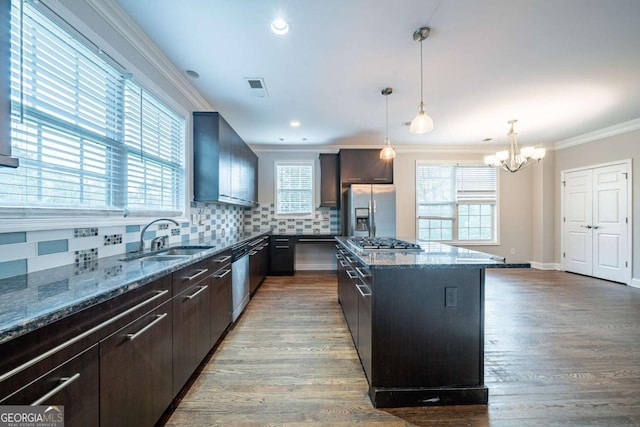 kitchen featuring a notable chandelier, a sink, appliances with stainless steel finishes, decorative backsplash, and ornamental molding
