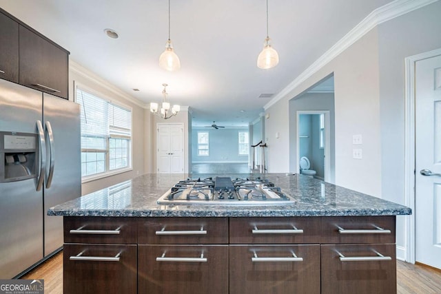 kitchen featuring ornamental molding, stainless steel appliances, dark brown cabinets, decorative light fixtures, and light wood-type flooring