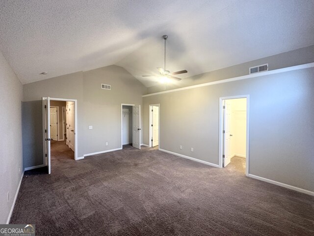 unfurnished bedroom with lofted ceiling, a textured ceiling, visible vents, and a walk in closet