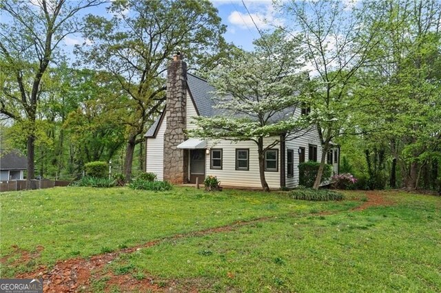 view of property exterior with a chimney and a lawn