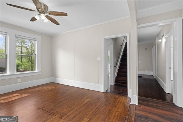 unfurnished living room featuring baseboards, stairway, crown molding, ceiling fan, and wood finished floors