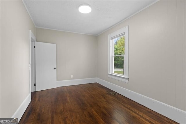 empty room with visible vents, baseboards, ornamental molding, and wood finished floors