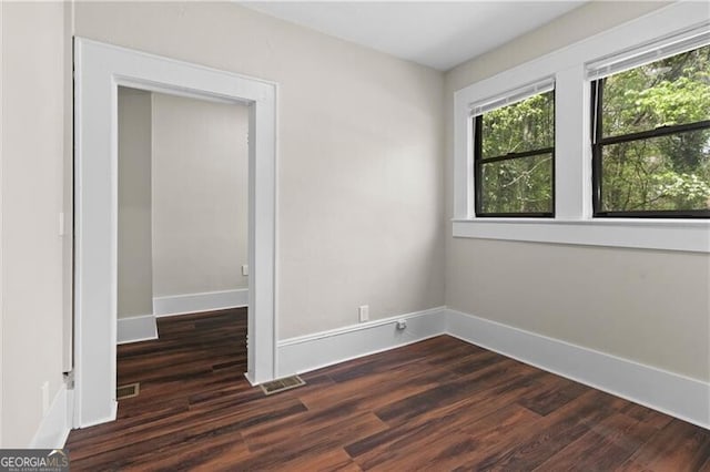 empty room with wood finished floors, baseboards, and visible vents