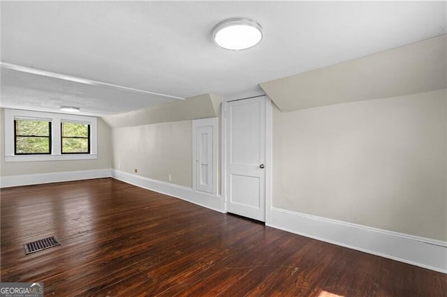 bonus room featuring lofted ceiling, visible vents, baseboards, and wood finished floors