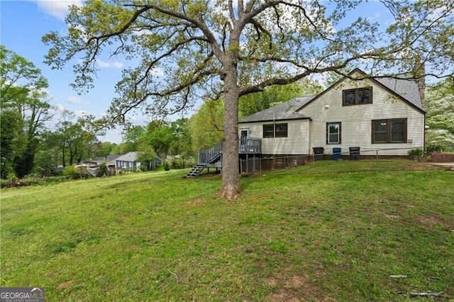 rear view of house featuring a lawn, a wooden deck, and stairs