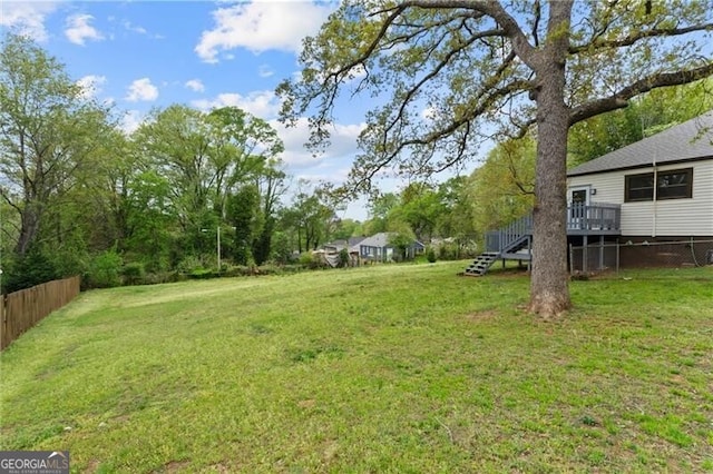view of yard featuring stairway, a deck, and fence