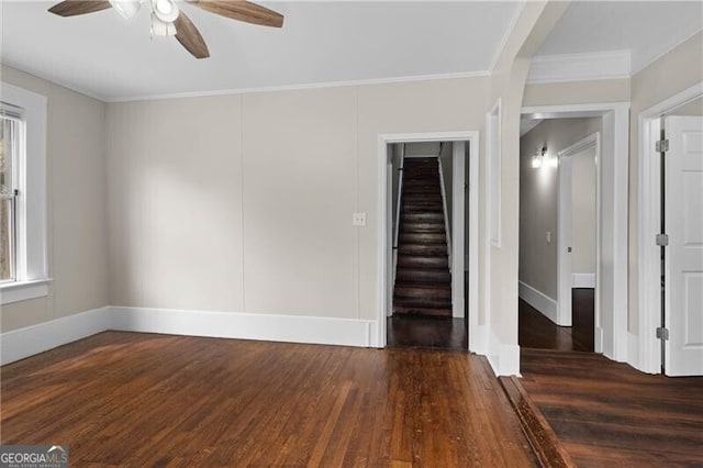interior space with baseboards, crown molding, stairs, ceiling fan, and wood finished floors