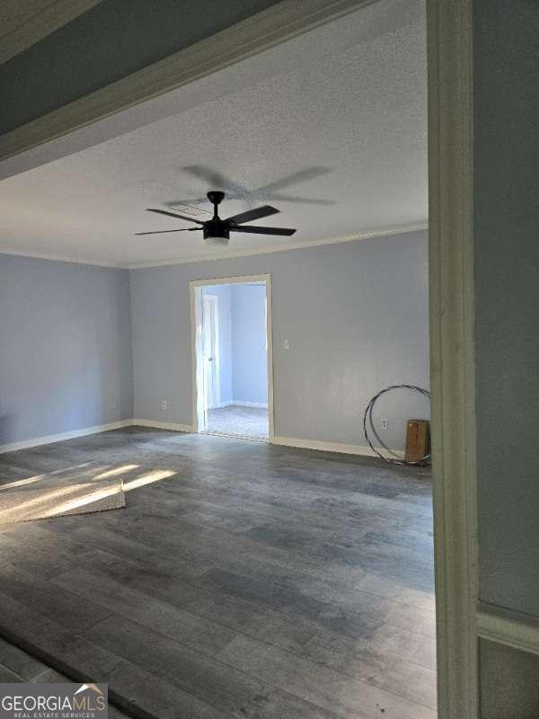 empty room featuring baseboards, a textured ceiling, ceiling fan, and wood finished floors