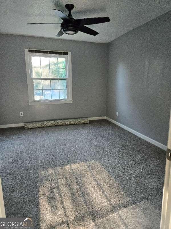 spare room featuring baseboards, carpet, and a ceiling fan
