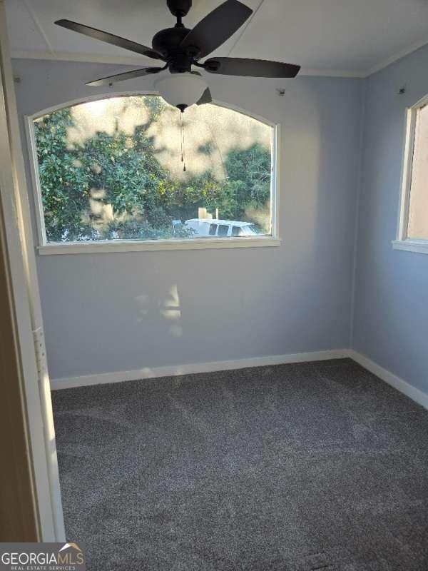 carpeted empty room featuring baseboards, ceiling fan, and crown molding