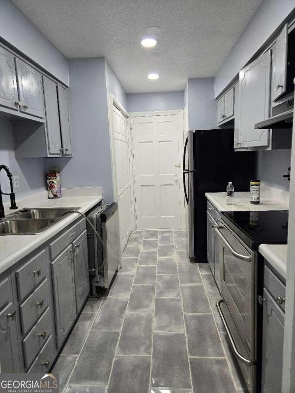 kitchen with electric range, light countertops, a sink, and gray cabinetry