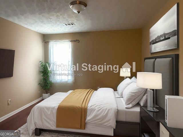 bedroom featuring baseboards, wood finished floors, and visible vents