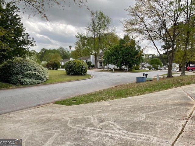 view of road with a residential view, curbs, and street lights