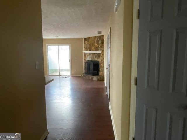 unfurnished living room featuring baseboards, wood finished floors, a textured ceiling, and a fireplace