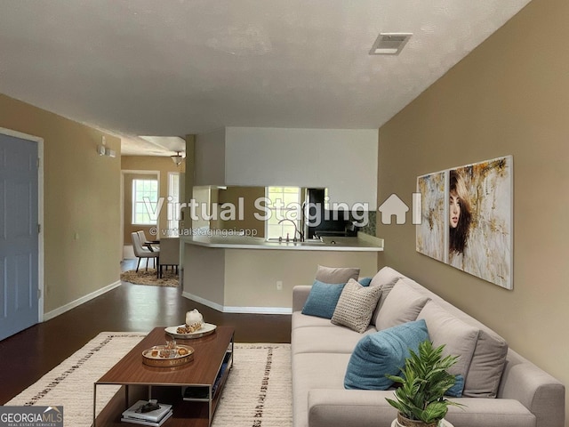 living area featuring visible vents, baseboards, and wood finished floors
