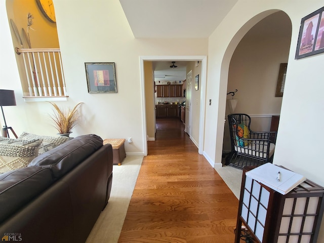 corridor featuring baseboards, wood finished floors, and arched walkways